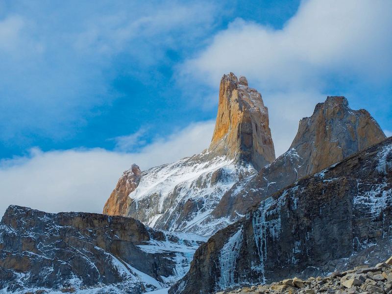 A golden granite tower rising out of snow and cloud.